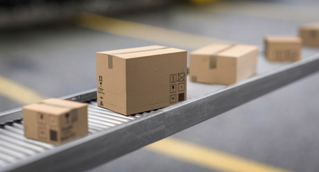 Boxes travelling along a powered roller conveyor